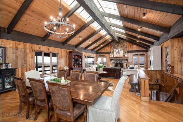 dining room with a chandelier, wood ceiling, lofted ceiling with skylight, wood finished floors, and wood walls
