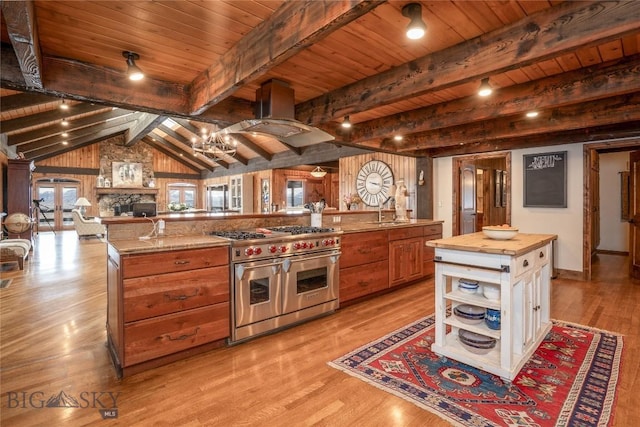 kitchen with island exhaust hood, a large island, wood ceiling, butcher block counters, and range with two ovens