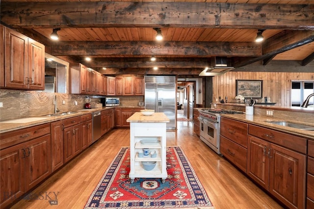 kitchen with high end appliances, a sink, open shelves, and light wood-type flooring