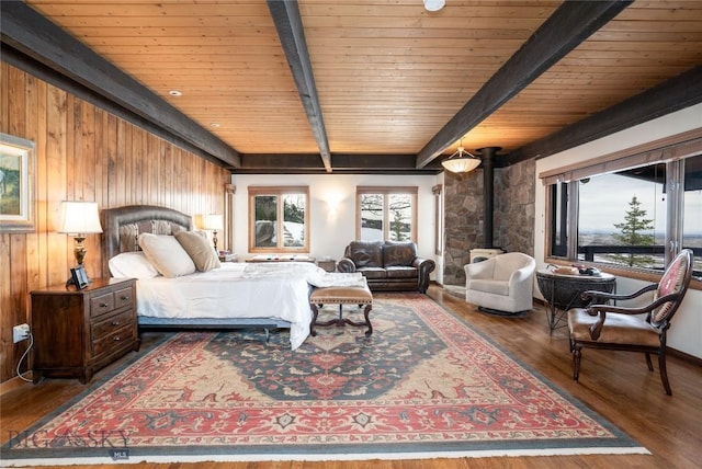 bedroom with wood finished floors, a wood stove, wooden walls, and beam ceiling