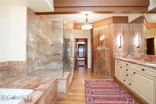 full bathroom with a sink, beamed ceiling, a shower stall, double vanity, and wood finished floors