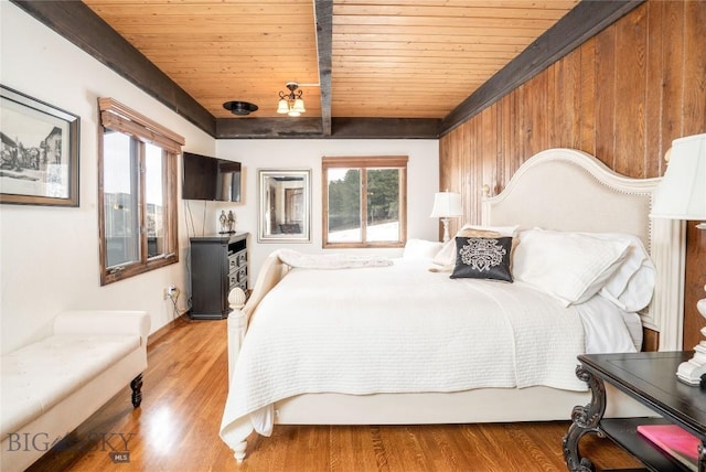 bedroom with beamed ceiling, wood finished floors, and wood ceiling