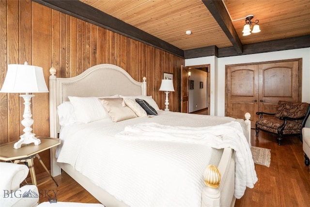 bedroom featuring beam ceiling, wood walls, wood finished floors, and wood ceiling
