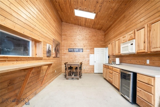 kitchen featuring light brown cabinetry, white microwave, vaulted ceiling, wood walls, and beverage cooler