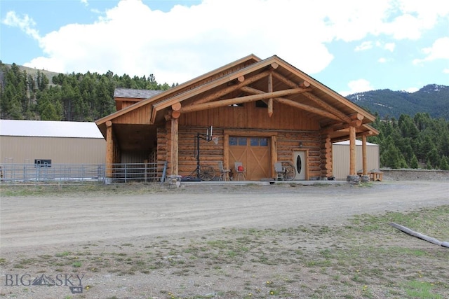 569/571 Cinnabar Basin Rd, Gardiner, MT 59030 - view of front of home featuring log exterior, an outdoor structure, a garage, a mountain view, and dirt driveway
