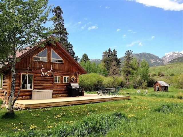 569/571 Cinnabar Basin Rd, Gardiner, MT 59030 - back of property with a deck with mountain view, an outbuilding, log exterior, and a lawn