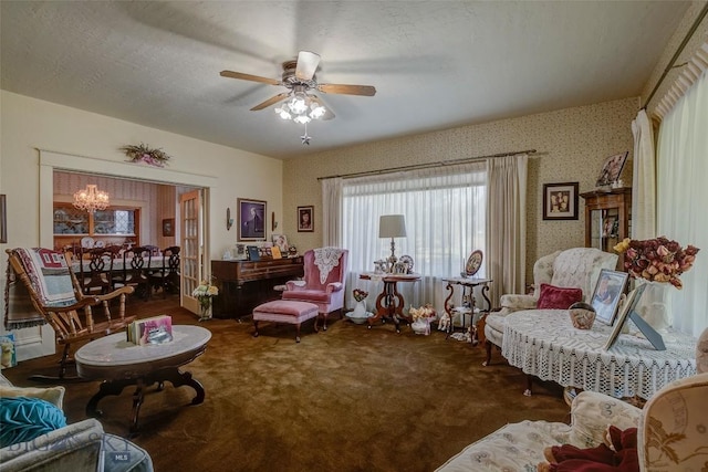 carpeted living room with ceiling fan with notable chandelier