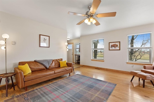 living area with a wealth of natural light, light wood-type flooring, and baseboards