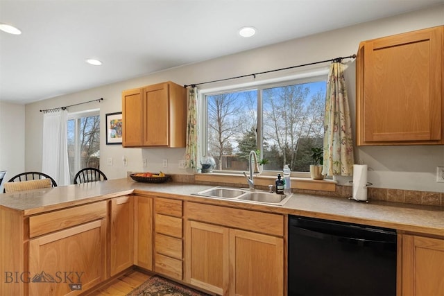 kitchen featuring black dishwasher, a sink, a peninsula, recessed lighting, and light wood-style flooring