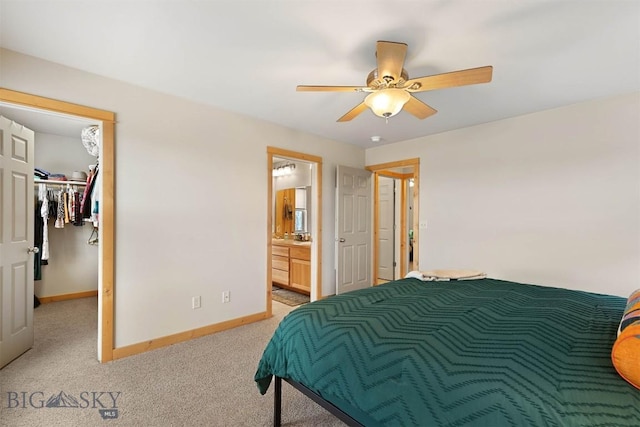 bedroom featuring carpet, ensuite bath, a ceiling fan, a spacious closet, and baseboards