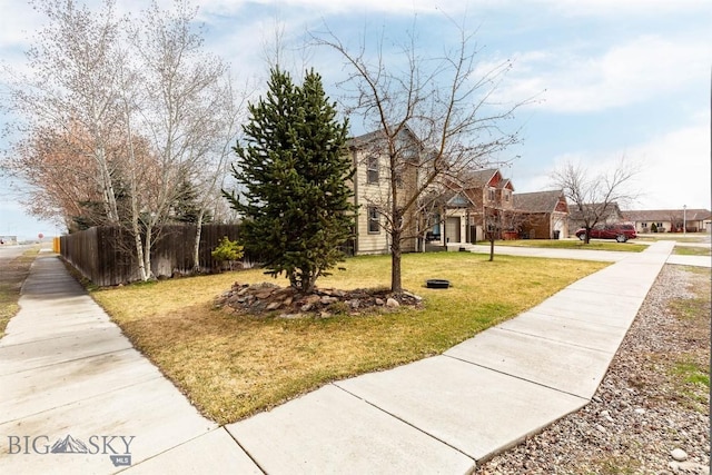 exterior space featuring concrete driveway, a front yard, and fence