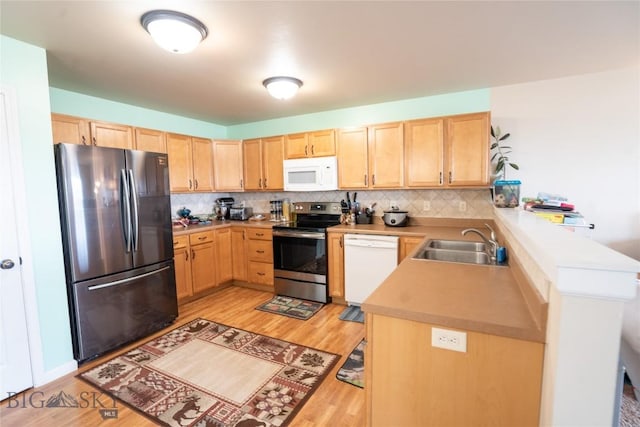 1112 Biehl Unit A, Belgrade, MT 59714 - kitchen featuring a peninsula, light wood-type flooring, appliances with stainless steel finishes, a sink, and light brown cabinets