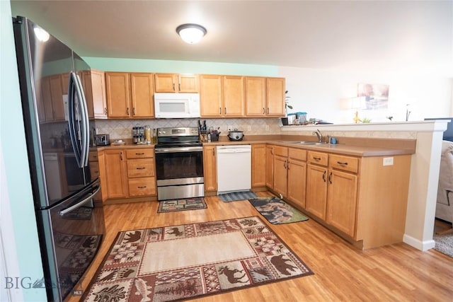 1112 Biehl Unit A, Belgrade, MT 59714 - kitchen with decorative backsplash, a peninsula, appliances with stainless steel finishes, and light wood finished floors