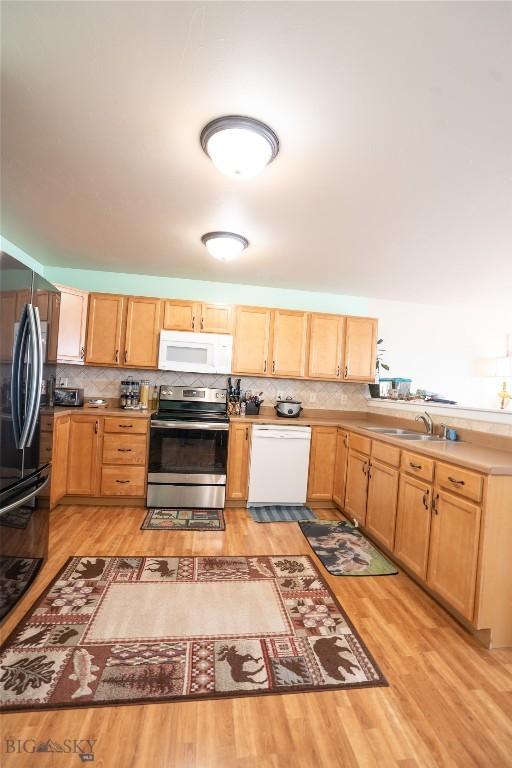 1112 Biehl Unit A, Belgrade, MT 59714 - kitchen featuring tasteful backsplash, white appliances, a sink, and light brown cabinetry