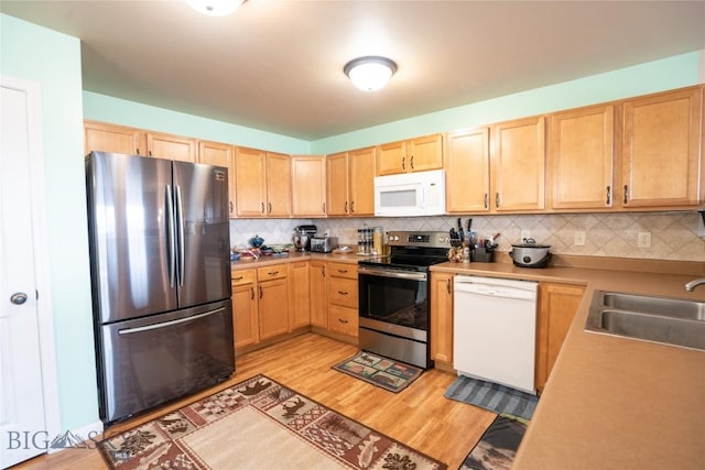 1112 Biehl Unit A, Belgrade, MT 59714 - kitchen featuring light brown cabinetry, light wood finished floors, a sink, and stainless steel appliances