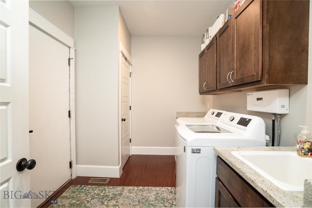 clothes washing area featuring a sink, baseboards, separate washer and dryer, cabinet space, and dark wood-type flooring