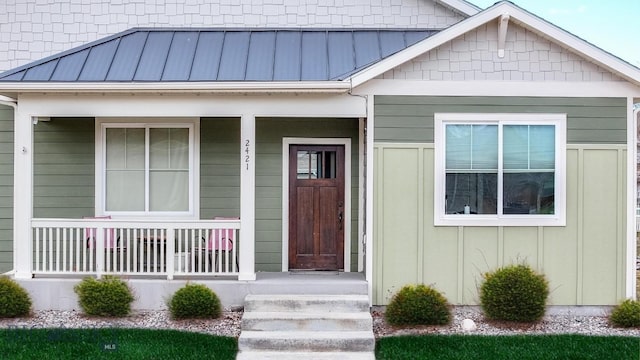property entrance with a porch, a standing seam roof, and metal roof