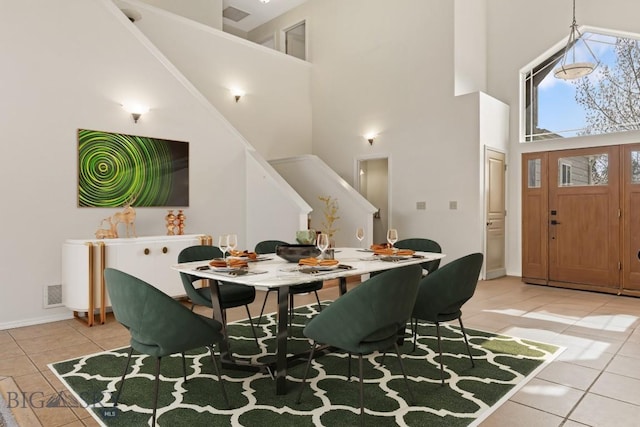 2514 Putter Ct, Bozeman, MT 59715 - dining area featuring light tile patterned floors, visible vents, stairway, a high ceiling, and baseboards