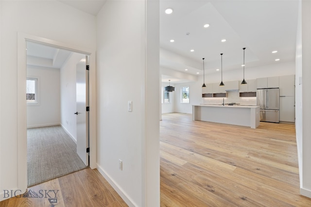 2806 S 30th Ave, Bozeman, MT 59718 - hallway featuring light wood-style floors, recessed lighting, a raised ceiling, a sink, and baseboards