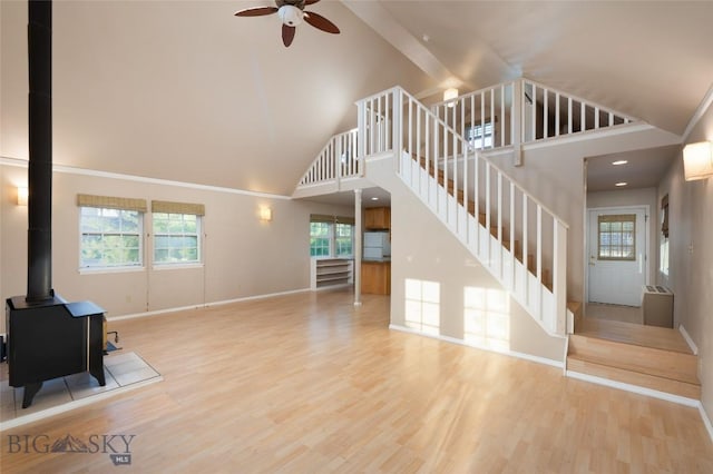 unfurnished living room with baseboards, high vaulted ceiling, wood finished floors, and stairway