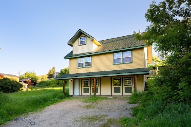 view of front facade featuring covered porch and gravel driveway