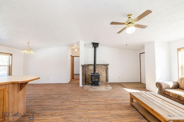 1319 Mcclellan, West Yellowstone, MT 59758 - living area with a textured ceiling, a wood stove, light wood-style flooring, ceiling fan, and a chandelier