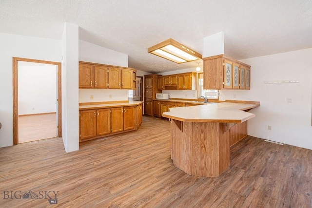 1319 Mcclellan, West Yellowstone, MT 59758 - kitchen with a peninsula, lofted ceiling, light wood-style floors, light countertops, and brown cabinetry