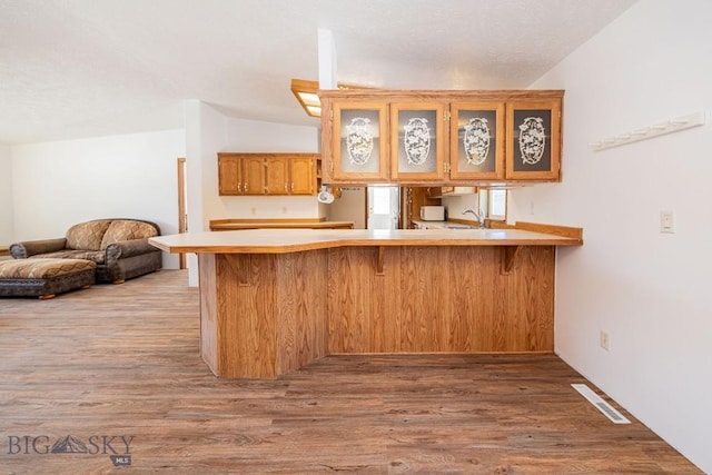 1319 Mcclellan, West Yellowstone, MT 59758 - kitchen with a kitchen bar, light countertops, glass insert cabinets, wood finished floors, and vaulted ceiling
