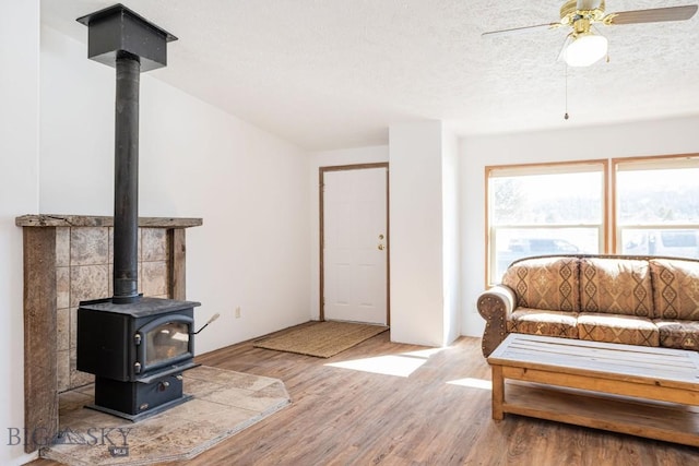 1319 Mcclellan, West Yellowstone, MT 59758 - living area with wood finished floors, a wood stove, a textured ceiling, and a ceiling fan