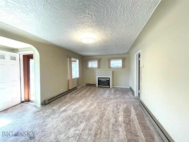 415 E Geyser, Livingston, MT 59047 - unfurnished living room featuring a baseboard radiator, arched walkways, a glass covered fireplace, and a textured ceiling