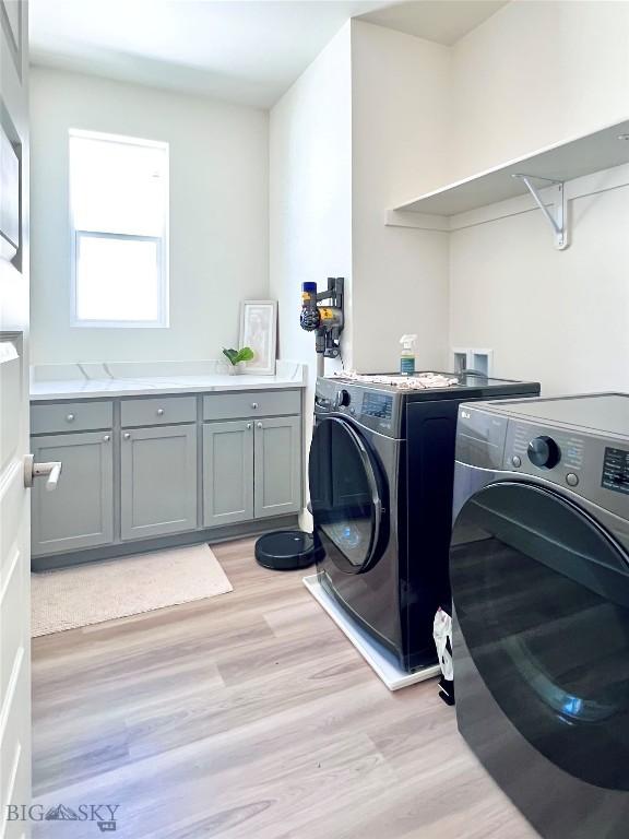 1823 N Cottonwood Rd, Bozeman, MT 59718 - clothes washing area with independent washer and dryer, light wood-style flooring, and cabinet space