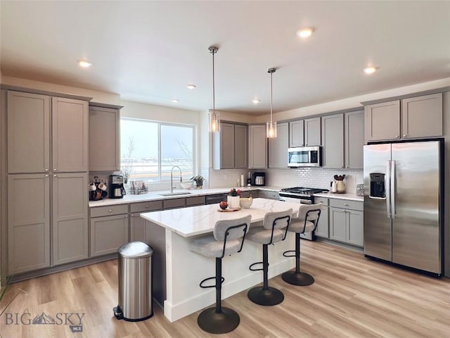 1823 N Cottonwood Rd, Bozeman, MT 59718 - kitchen with stainless steel appliances, gray cabinetry, a sink, light wood finished floors, and tasteful backsplash