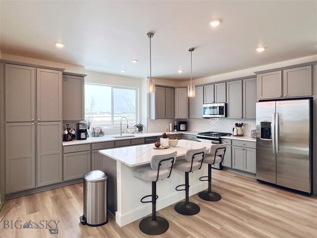 1823 N Cottonwood Rd, Bozeman, MT 59718 - kitchen featuring appliances with stainless steel finishes, gray cabinetry, a sink, light wood-type flooring, and backsplash