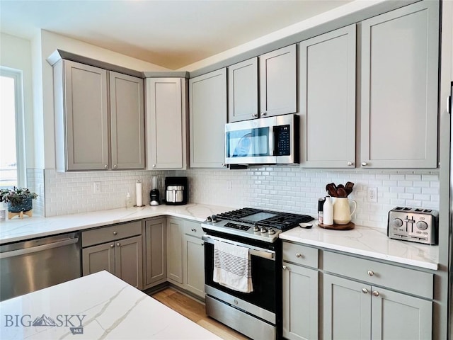 1823 N Cottonwood Rd, Bozeman, MT 59718 - kitchen with appliances with stainless steel finishes, gray cabinets, backsplash, and light stone counters