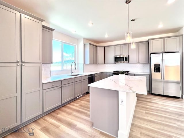 1823 N Cottonwood Rd, Bozeman, MT 59718 - kitchen featuring appliances with stainless steel finishes, gray cabinets, light wood finished floors, a center island, and backsplash