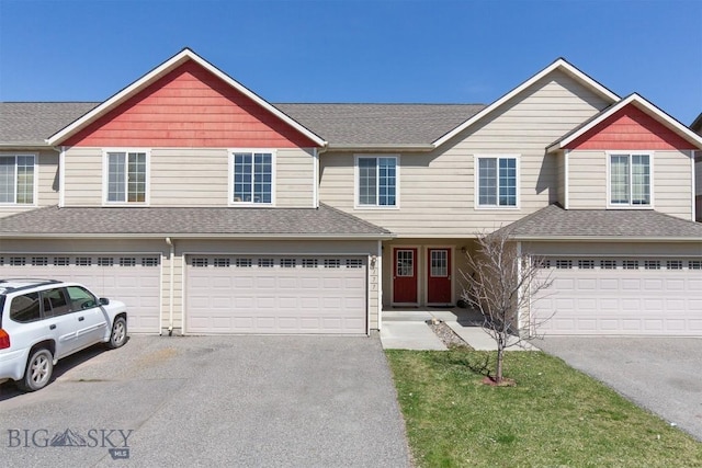 view of front of house with an attached garage, a shingled roof, and aphalt driveway