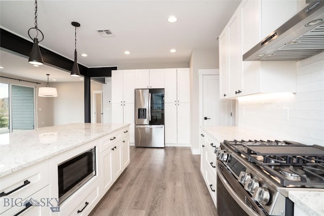 kitchen with light wood-style flooring, wall chimney range hood, white cabinetry, visible vents, and stainless steel appliances