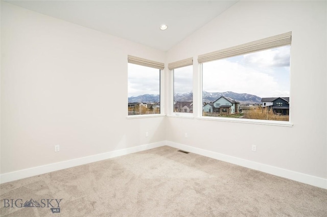 empty room featuring a mountain view, carpet floors, baseboards, and visible vents