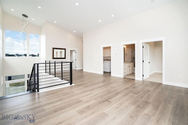 unfurnished living room featuring light wood finished floors, high vaulted ceiling, baseboards, and recessed lighting