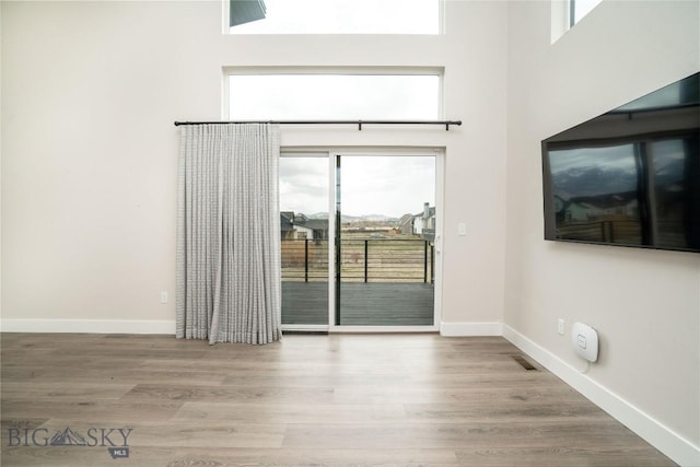 1610 Windrow Dr, Bozeman, MT 59718 - empty room featuring plenty of natural light, wood finished floors, baseboards, and a towering ceiling