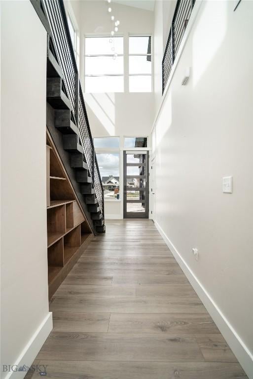 interior space with a high ceiling, wood finished floors, baseboards, and stairway