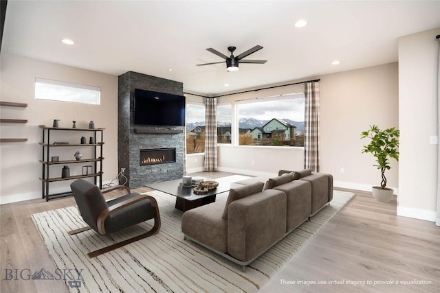 living area with baseboards, a ceiling fan, recessed lighting, wood finished floors, and a large fireplace
