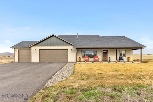 ranch-style home featuring a front lawn, aphalt driveway, board and batten siding, an attached garage, and a porch