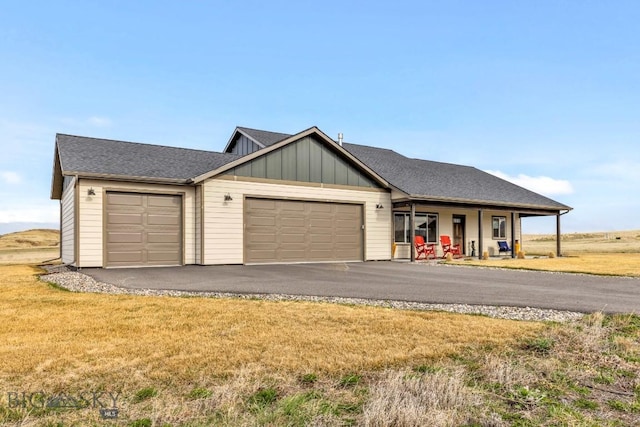 ranch-style home featuring board and batten siding, an attached garage, a front yard, and aphalt driveway