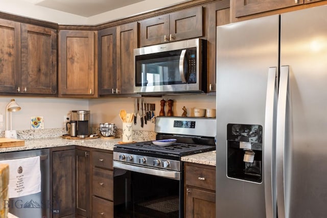 kitchen with light stone counters, dark brown cabinetry, and stainless steel appliances