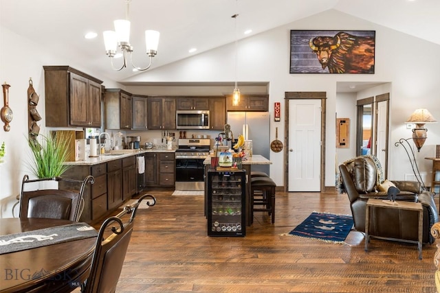 kitchen with a kitchen breakfast bar, an inviting chandelier, dark brown cabinets, a sink, and appliances with stainless steel finishes