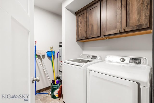 clothes washing area with cabinet space, washing machine and dryer, baseboards, and light tile patterned floors