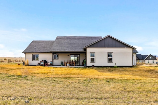back of property with a lawn, a patio area, and board and batten siding