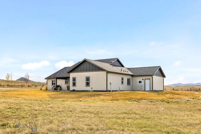 back of property featuring roof with shingles, a yard, and board and batten siding