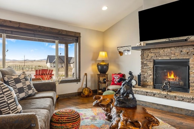 living area featuring a stone fireplace, wood finished floors, baseboards, lofted ceiling, and recessed lighting